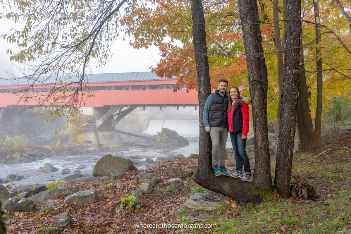 Man and woman posing for a photo in from of the Taftsville Covered Bridge