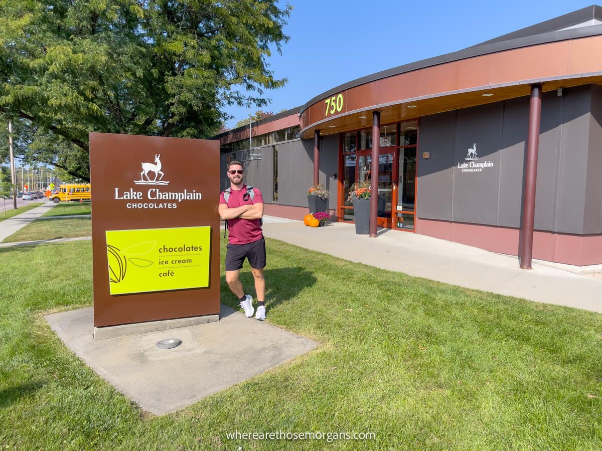 Man leaning up against the sign for Lake Champlain Chocolates