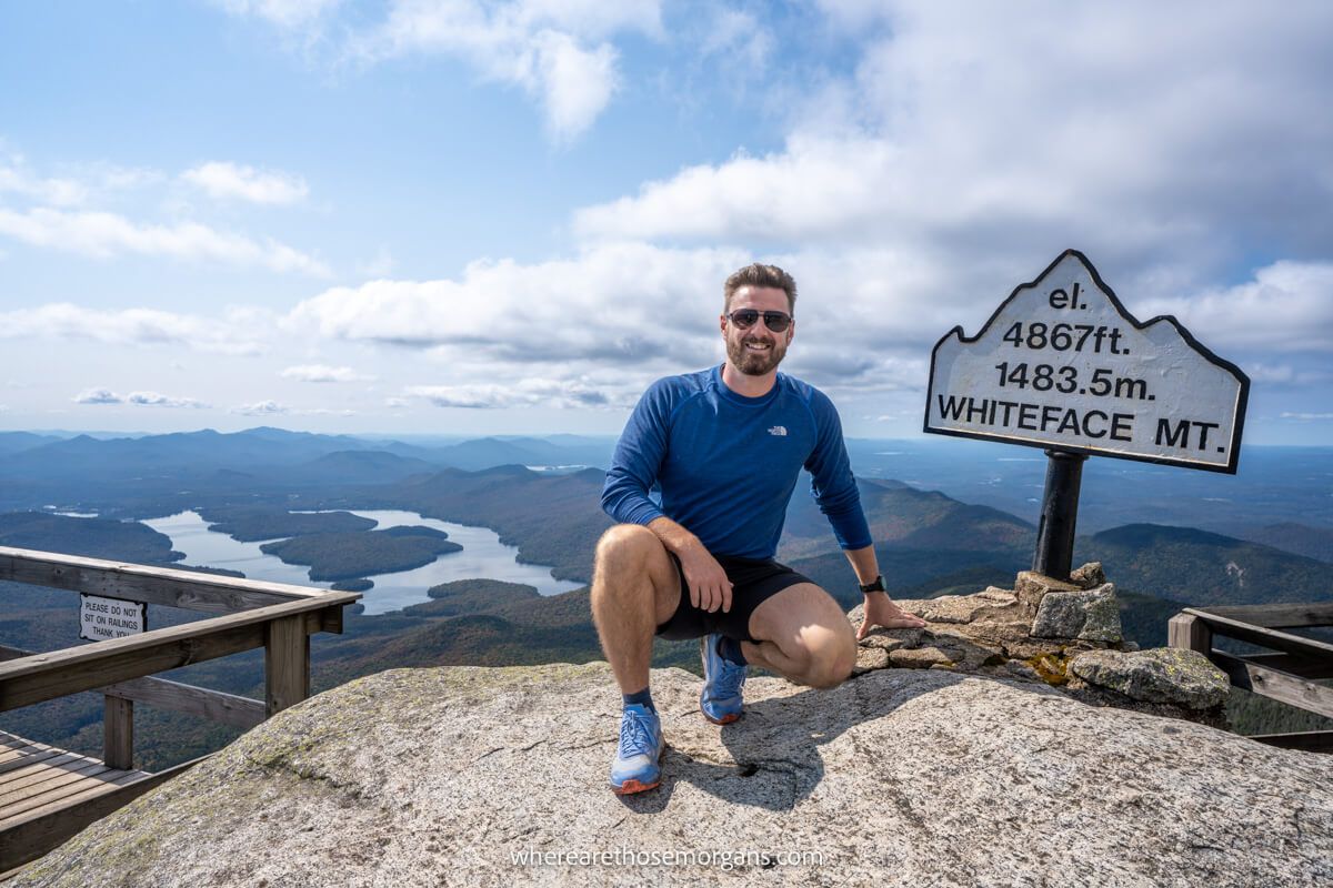 Man taking a photo with the Whiteface Mountain summit sign near Lake Placid