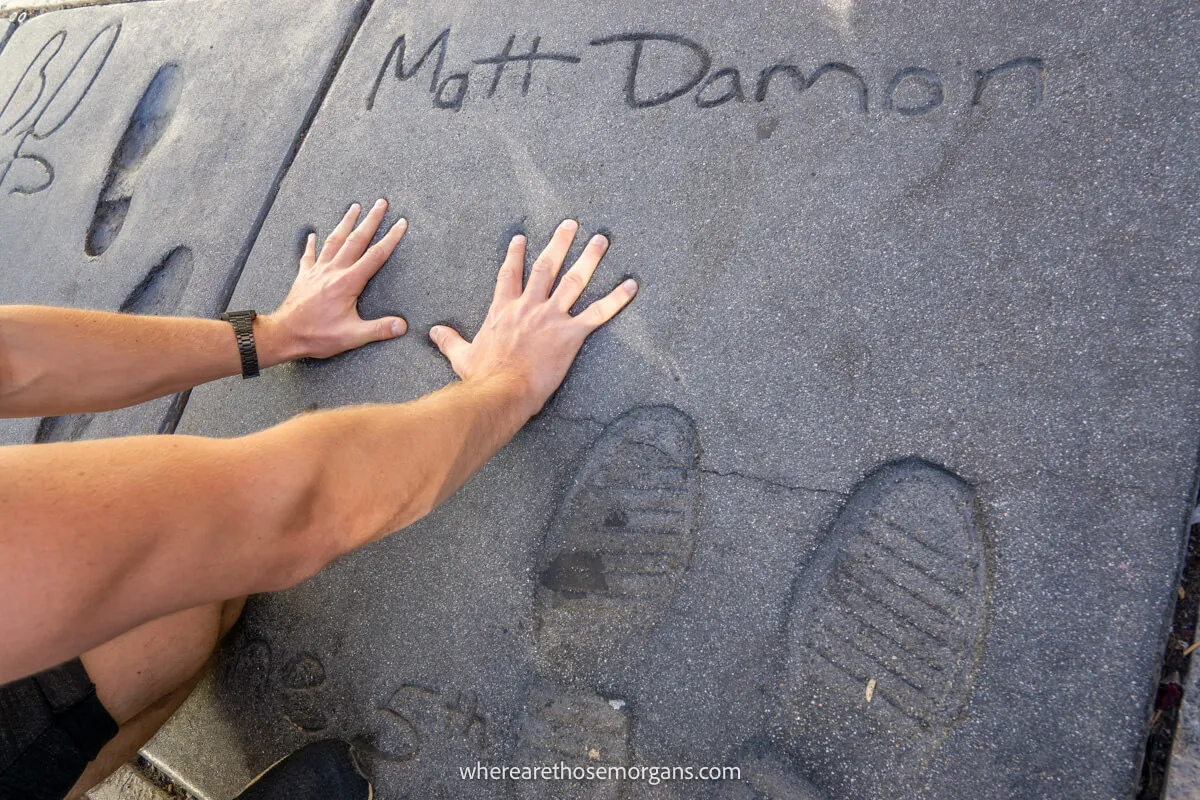 Man putting his hands into Matt Damon's fingerprints at the TCL Chinese Theater