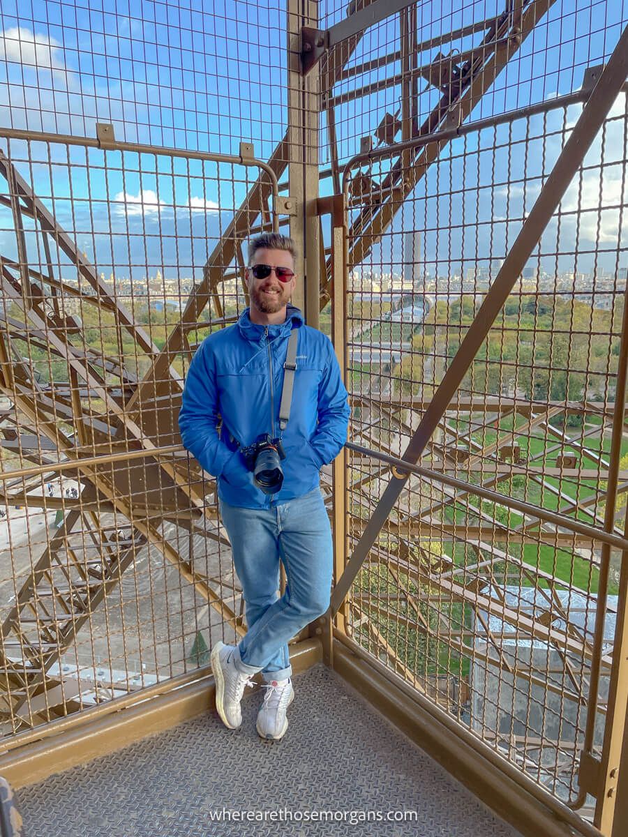 Man standing in the stairs leading up to the Eiffel Tower, one of the best things to do in Paris