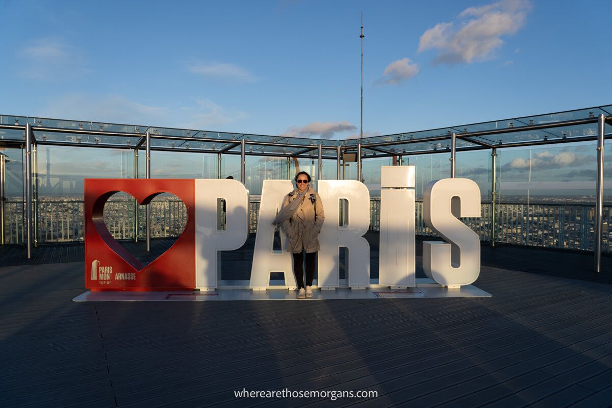 Woman standing with the I love Paris sign at the Montparnasse Tower Observation Deck