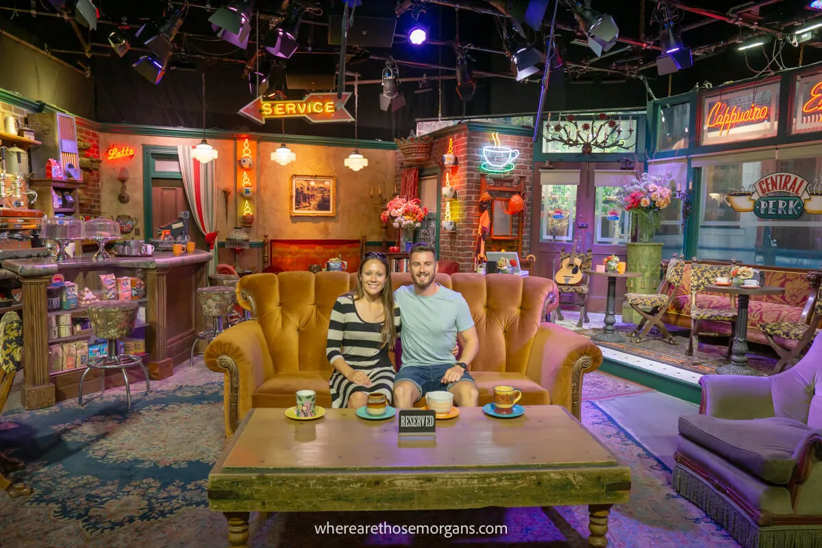 Man and woman sitting on the couch on the Friends set at Central Perk