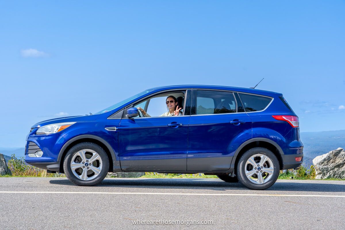 Woman driving a blue SUV up the Whiteface Mountain Highway in fall