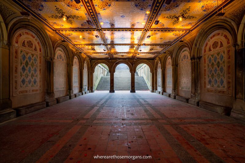 Inside Bethesda Terrace in Central Park at sunrise with orange tiled ceiling lighting up and no people around