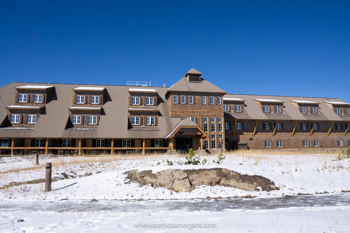 Exterior photo of a low and long hotel complex behind a snowy ground and underneath a clear blue sky