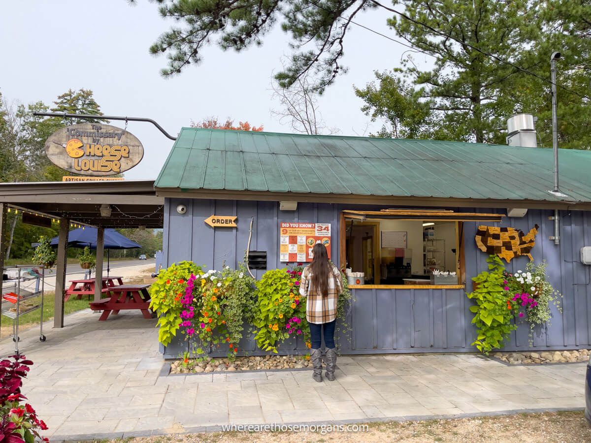 Tourist standing at the serving window of a wooden building offering food with tables outside