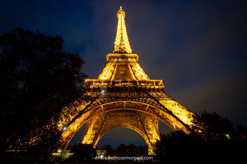 Looking up at the Eiffel Tower lit up orange at night