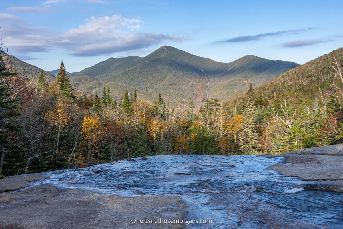 Lowe running waterfall cascading over a shelf with far reaching views over trees and hills at Indian Falls on the Mount Marcy hike in New York