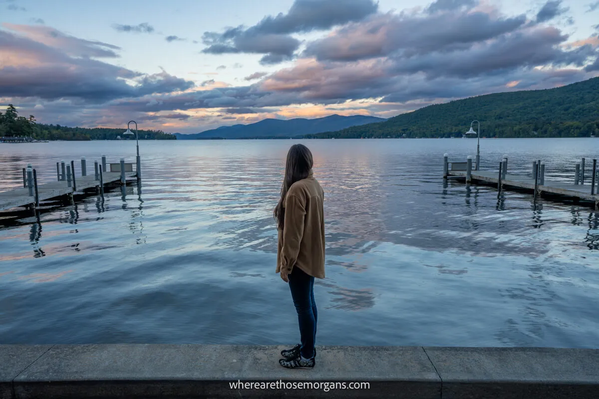 Tourist stood on a wall looking at a lake during sunset