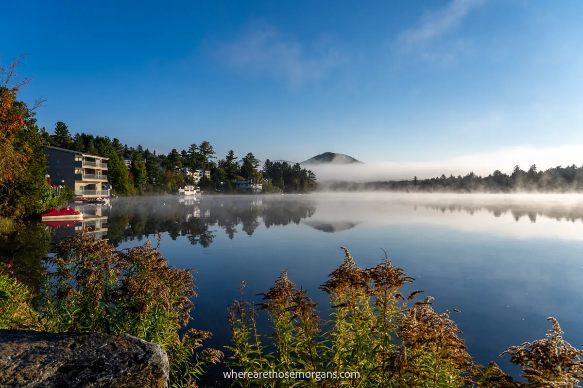 The shores of a still lake with fog rising at dawn