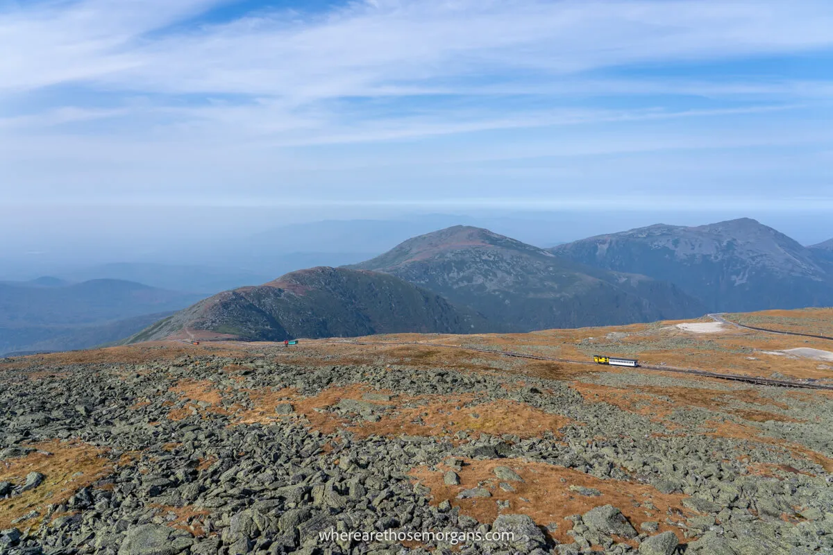 Cog trains on a railway line going down Mt Washington with views as far as the eye can see on a clear day