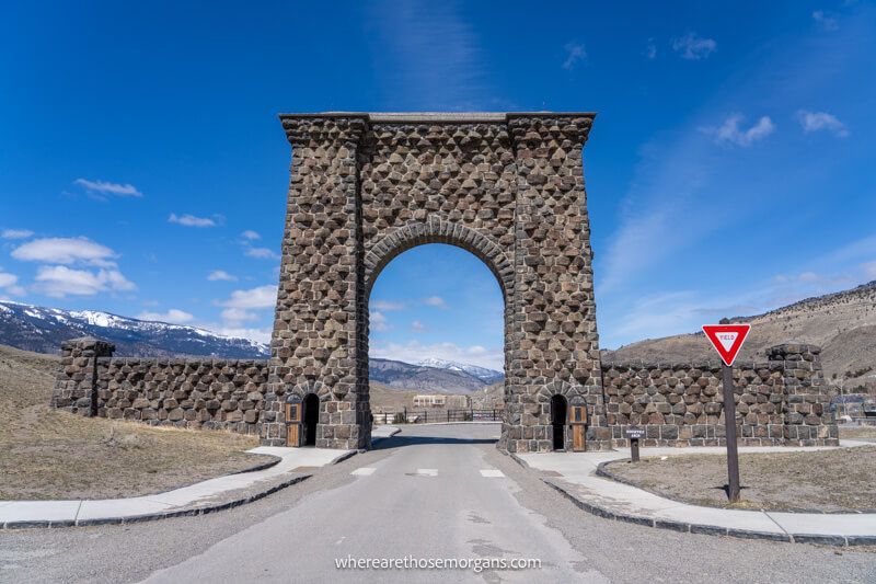 Large stone arch with a road running through and a yield sign