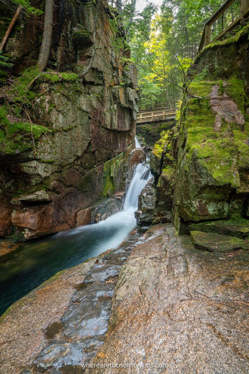 Narrow gorge with a waterfall and moss clad walls in a forest on the Kancamagus Highway in New Hampshire