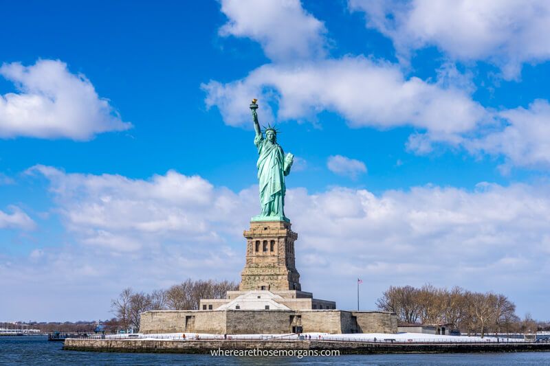 The Statue of Liberty holding her torch high from close to Liberty Island with snow on the ground