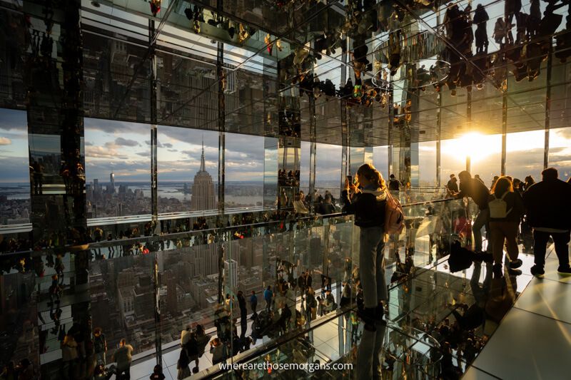 Sunset at Summit One Vanderbilt with lots of mirrors on all walls, floor and ceiling reflecting people and sunlight