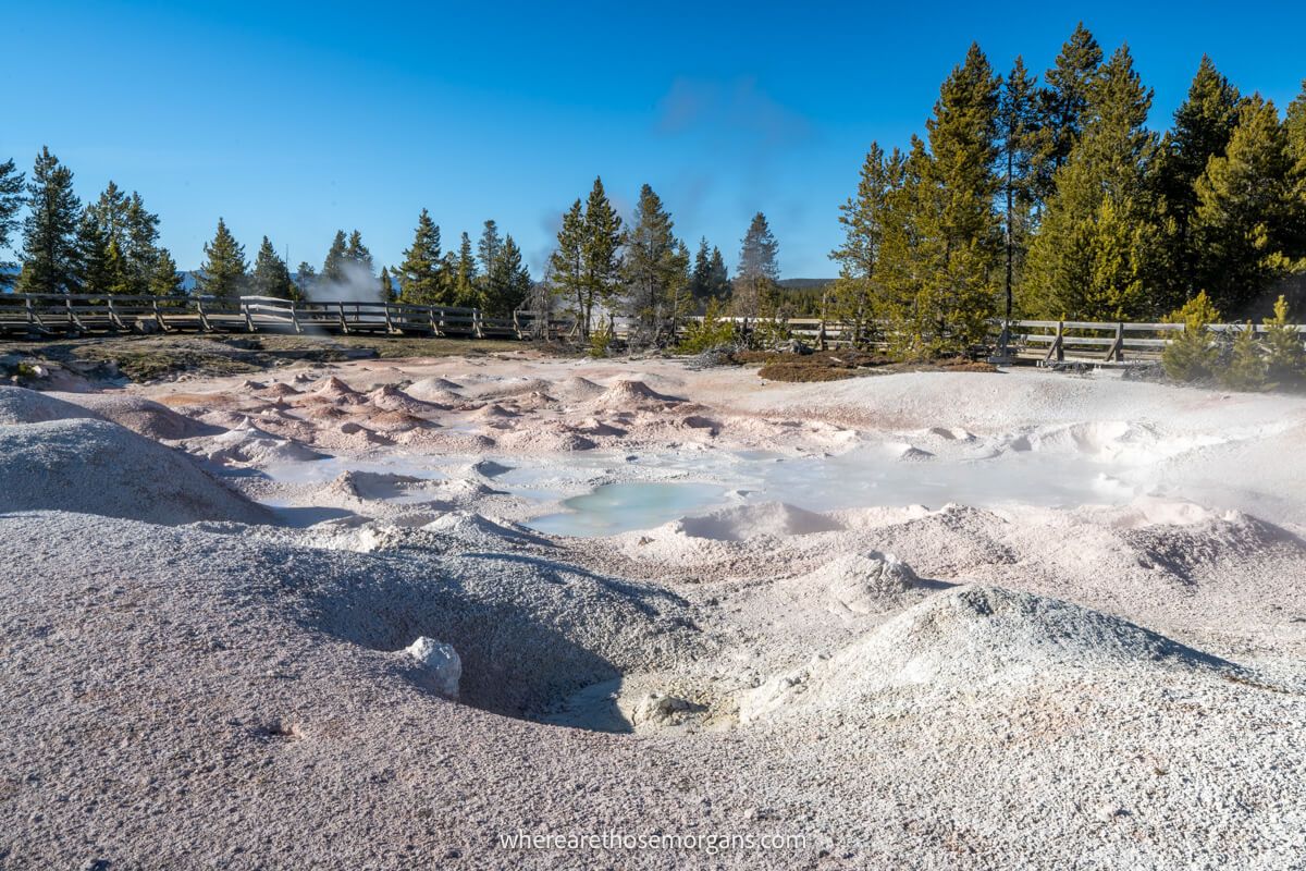 Shallow geyser surrounded by white terrain and light billowing steam