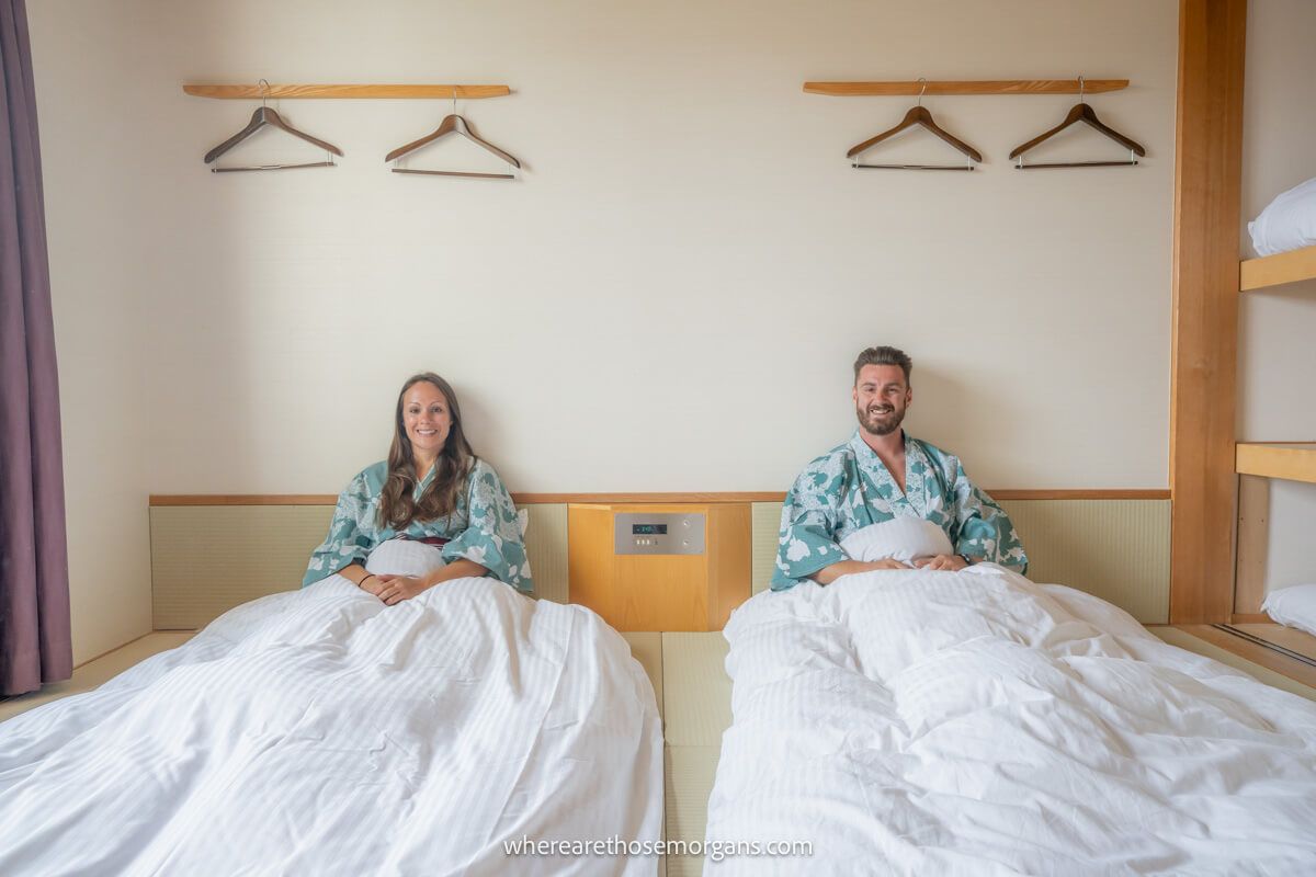 Photo of a couple in robes sitting up in twin beds on the floor in a traditional Japanese ryokan