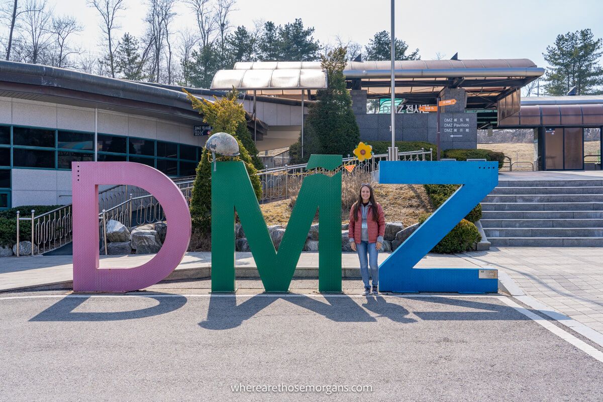 Photo of a tourist standing next to three tall letters DMZ in Korea