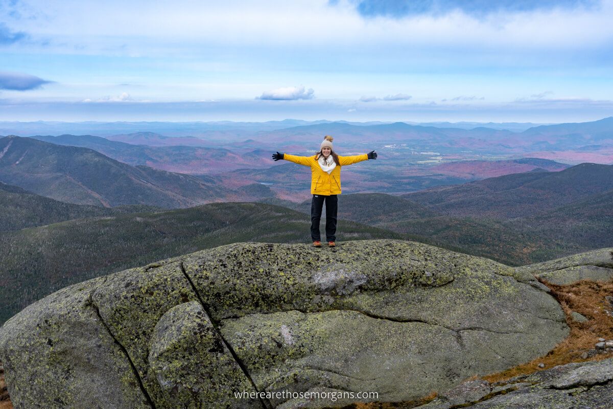 Hiker at the summit of Mount Marcy in New York with distant views