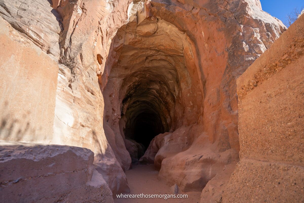The entrance to a tunnel carved through red rocks with walls to either side