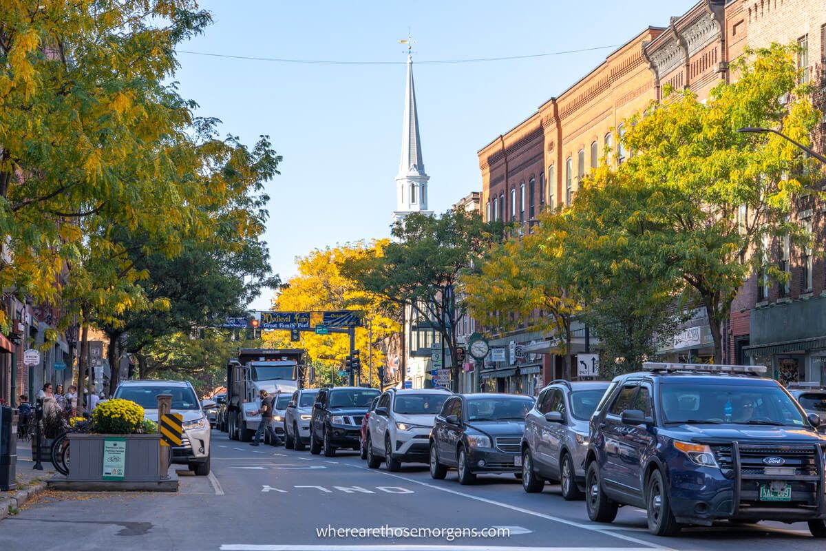 Cars in a traffic jam on a town road with buildings trees and a church spire