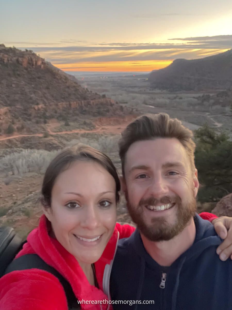 Close up selfie photo of a couple at the summit of Dinosaur Prints Trail at sunset near Kanab Utah