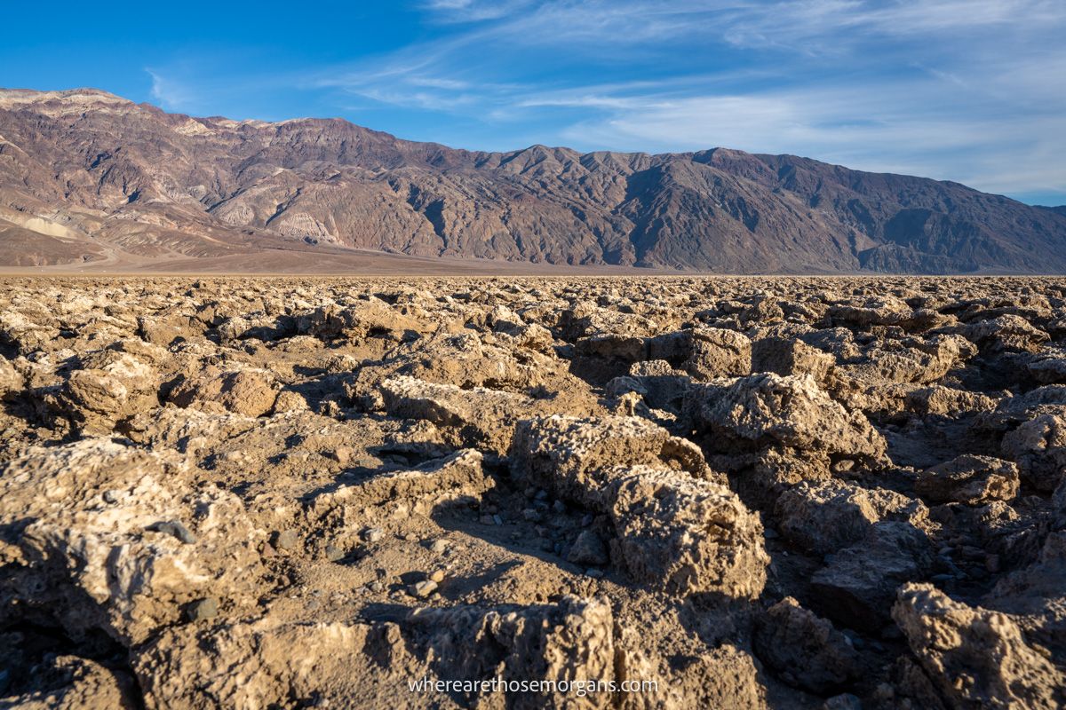 Wide open and flat landscape with jagged rocks leading to tall mountains in the background