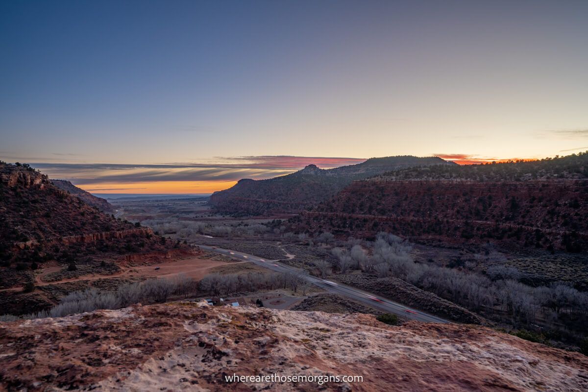 Sunset view over a red rock landscape from a small hiking summit with soft colors in the sky