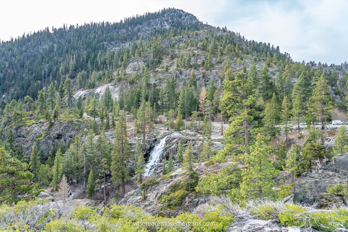 Distant view over a powerful waterfall cascading down a rocky landscape surrounded by trees and hills