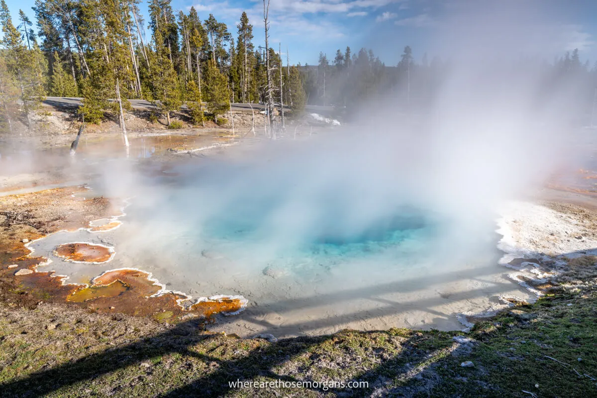 Photo of a lightly steaming blue hot spring in Wyoming