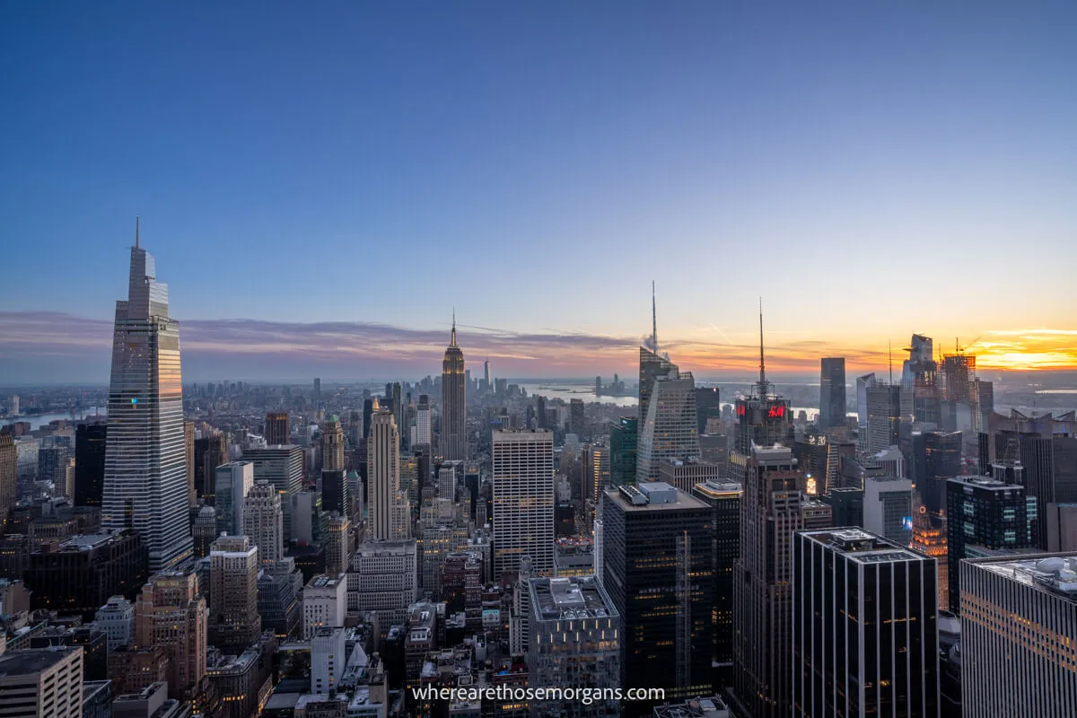 The New York City skyline at sunset from high up on an observation deck with views across all of Manhattan and soft colors in the sky