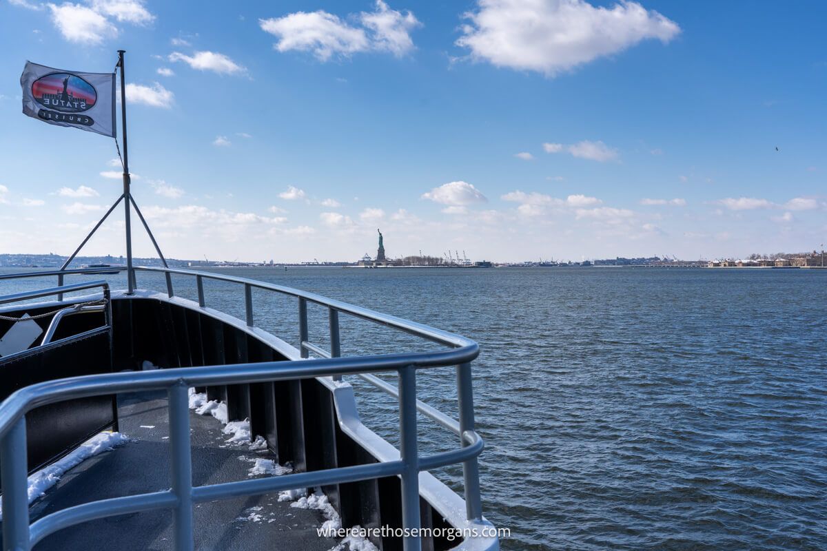 Photo of the outer deck of a boat on water with a flag flying and blue sky