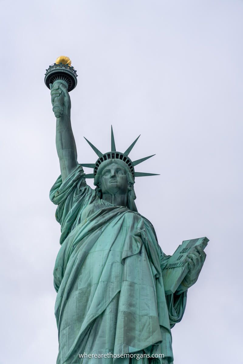 Photo of a front on close up view from below the Statue of Liberty on a cloudy day