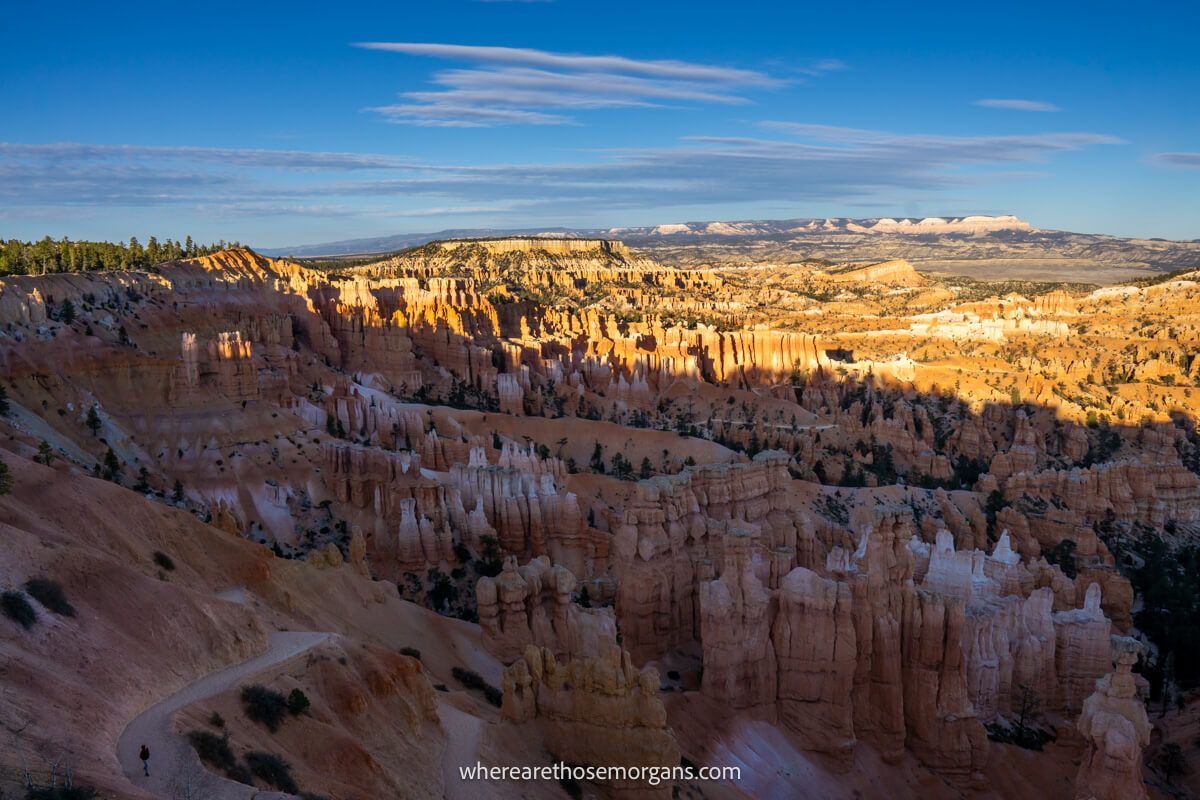 View over a sandstone bowl-shaped amphitheater with rugged hoodoos and spires half covered in shadow and half in light at sunset from Sunset Point in Bryce Canyon